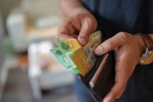 Person counting Australian cash from a wallet, representing AML property transactions in Queensland.
